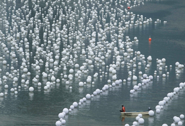 Работник делает передышку, пока плывёт вдоль  Marina Bay в Сингапуре 30 декабря 2013 года. Люди написал свои пожелания на Новый год на сферах, а потом сферы положили в реку. (Лоу Южин / Reuters)