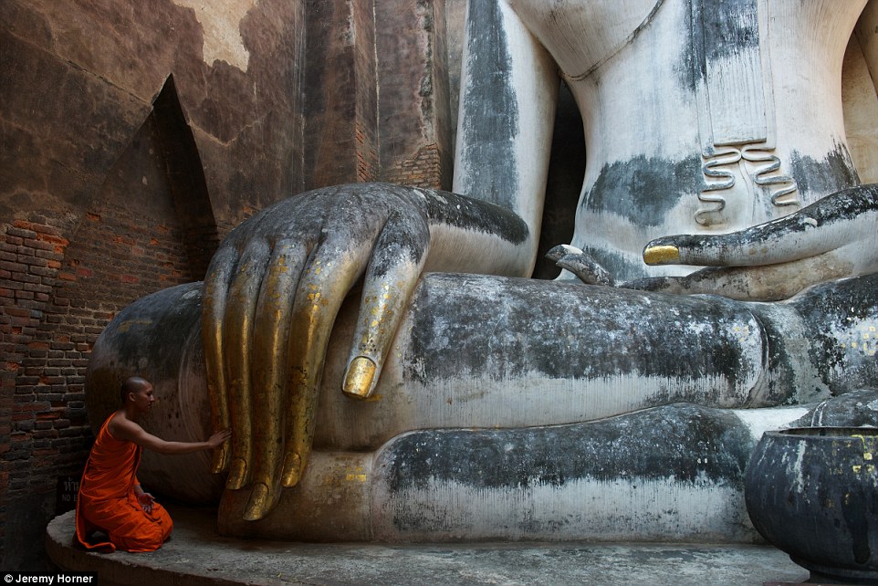 Статуя Будды возле храма Ват Си Чхум в Таиланде. Посетители могут взглянуть на статую через узкий просвет в стене храма.